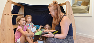 Educator with two small children looking at picture book