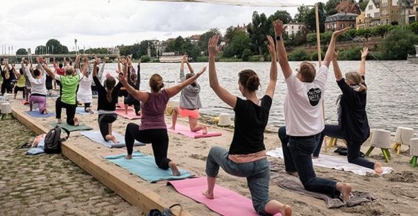 Zahlreiche Veranstaltungen brachten im Rahmen der Aktion „Neckarorte“ auch im Jahr 2017 Leben an den Fluss, wie beispielsweise das Neckar-Anbaden, das Neckar-Erwachen oder die Neckarlounge am experimentellen Strand am Neckarlauer. (Foto: Arndt) Menschen machen Yoga-Übungen an einem künstlichen Sandstrand am Neckar.