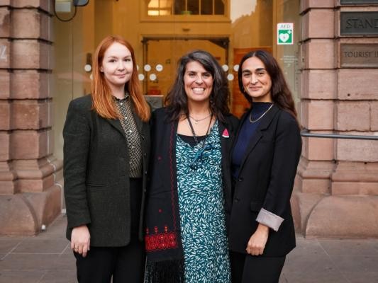 Der neue Vorstand des Migrationsbeirats der Stadt Heidelberg (von links): Anna Churaeva, Eva Paula Mendes de Oliveira Gomes und Mehtap Şahin-Marković. (Foto: Stadt Heidelberg) Drei lächelnde Frauen vor dem Heidelberger Rathaus