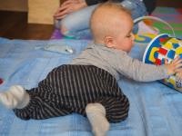 Baby auf Krabbeldecke (Foto: Jule Stephany) Ein Baby liegt bäuchlings auf einer Krabbeldecke und spielt mit einer leeren Bauklotz-Tonne (Foto: Jule Stephany)