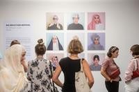 Der neue Leitfaden gegen Muslimfeindlichkeit enthält anschauliche Praxisbeispiele, um antimuslimischem Rassismus auf lokaler Ebene entgegen zu wirken und ein friedliches Zusammenleben zu stärken. Die Stadt Heidelberg ist mit dem Projekt der Jüdisch-Muslimischen Kulturtage vertreten, die beispielsweise wie hier mit Kunstausstellungen für muslimische Lebenswelten sensibilisiert. (Foto: Joe Pohl) Menschen stehen in einer Ausstellung vor Bildern.