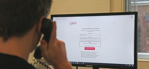 Mitarbeiter mit Telefon vor Computerbildschirm (Foto: Stadt Heidelberg) Mitarbeiter mit Telefon vor Computerbildschirm