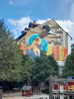 Das Mural in der Plöck passt perfekt zum Konzept der "Gassengalerie". (Foto: Stadt Heidelberg) Auf eine Hauswand ist ein buntes Bild gemalt: Ein schwarzer Mann hat einen Hund auf dem Schoß.