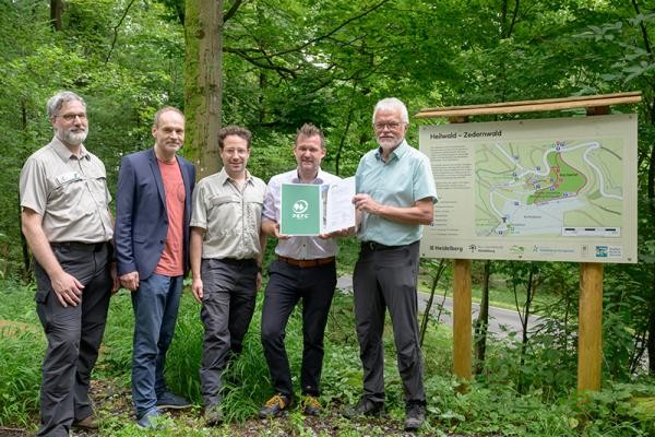 Umweltbürgermeister Raoul Schmidt-Lamontain (2.v.r.) freut sich mit Thorsten Stephan, Büroleiter des Stadtwalds beim Landschafts- und Forstamt, Stephan Hörl, Kaufmännischer Leiter der Rehaklinik Heidelberg-Königstuhl, und Stadtforstdirektor Tillmann Friederich (v.l.) über die erneute Zertifzierung des Heidelberger Stadtwalds als „Kur- und Heilwald“ durch Auditor Wilfried Stech (r.). (Foto: Philipp Rothe) Männer vor einem Waldschild