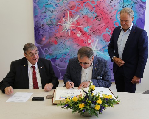 Der ukrainische Botschafter Oleksii Makeiev trug sich am Montag, 23. September 2024, im Rathaus im Beisein von Oberbürgermeister Eckart Würzner in das Goldene Buch der Stadt Heidelberg ein. (Foto: Stadt Heidelberg) Ein Mann trägt sich in ein schweres aufgeschlagenes Buch ein, er wird flankiert von zwei weiteren Männern.