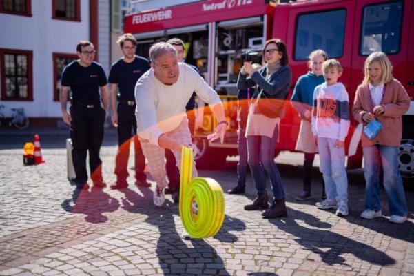 Oberbürgermeister Eckart Würzner beantwortete beim Kindertag im und rund um das Rathaus in Sprechstunden Fragen der Schülerinnen und Schüler und ging mit ihnen an den Stationen auf Entdeckungstour, unter anderem bei der Jugendfeuerwehr. (Foto: Dittmer) Oberbürgermeister Würzner wirft bei der Station der Feuerwehr am Kindertag einen Löschschlauch.