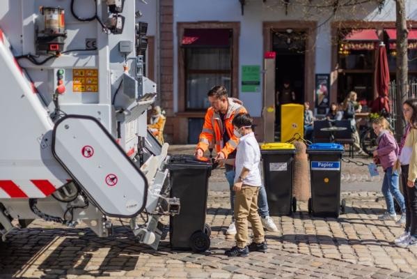 Mitanpacken erwünscht: Wo darf man schon einmal eine Mülltonne in einem echten Müllauto ausleeren? Beim Kindertag der Stadt Heidelberg natürlich. (Foto: Dittmer) Mitarbeiter der Abfallwirtschaft zeigt wie ein Müllauto Mülltonnen leert.