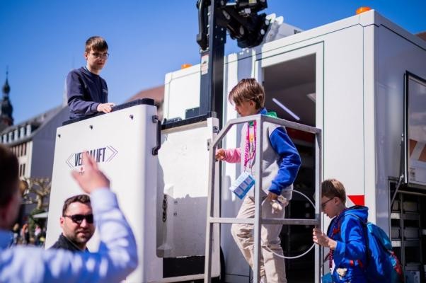 Die Stadtwerke Heidelberg erläuterten den Kindern beim Kindertag der Stadt Heidelberg, wie Glasfaser funktioniert. (Foto: Dittmer) Kind auf einer Treppe vor weißem Kontainer.