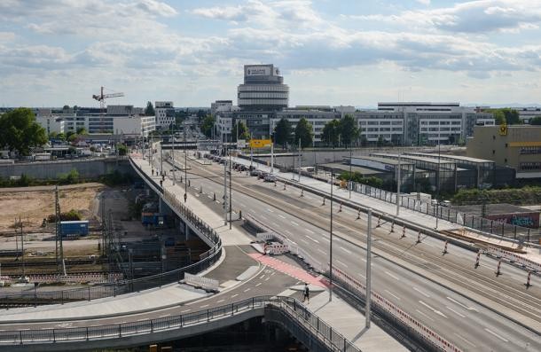 Die Montpellierbrücke wird über die Sommerferien – vom 31. Juli bis 14. September 2025 – stadtauswärts (im Bild rechts) vollgesperrt. (Foto: Stadt Heidelberg) Blick auf eine große mehrspurige Brücke über Eisenbahngleise.