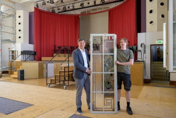 115 historische Holzfenster und rund 20 Fenster mit gläsernen Verzierungen aus den Jahren 1926 bis 1928 werden derzeit an der Musik- und Singschule saniert und überarbeitet. Erster Bürgermeister Jürgen Odszuck (l.) informiert sich bei seiner Sommertour über die Arbeiten. (Foto: Philipp Rothe) Erster Bürgermeister Jürgen Odszuck hält gemeinsam mit einem Mitarbeiter eines der betroffenen Fenster.