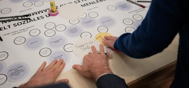Teamwork (Foto: Beekmann) Hände von 2 Personen beim Arbeiten an einem Plakat