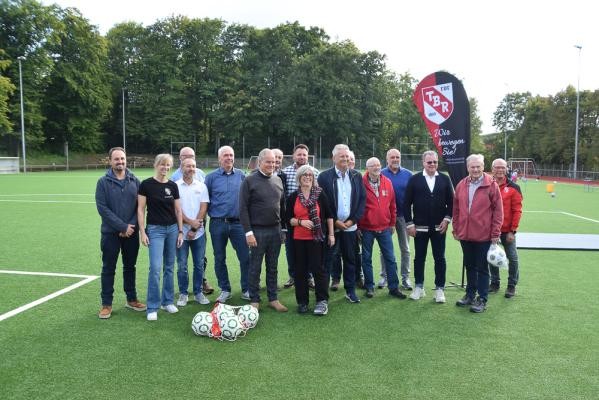 Oberbürgermeister Eckart Würzner (5. von links) freute sich gemeinsam mit dem Vorstand und Mitgliedern des Turnerbundes Rohrbach sowie weiteren Akteurinnen und Akteuren des Heidelberger Sports über die Eröffnung des fertig sanierten Sportplatzes. Eine Menschengruppe posiert auf einen Rasenplatz