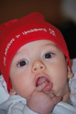 Welche Angebote gibt es für Familien mit Babys in Heidelberg? Eltern mit Neugeborenen lädt das Familienbüro am 26. November zu einer Infoveranstaltung in die Räume des Stadtteilvereins Boxberg ein. (Foto: J. Wetzel) Baby mit rotem Mützchen guckt in die Kamera.