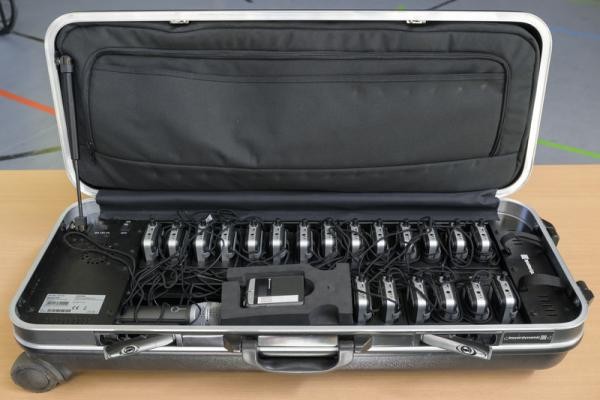 Induktionshöranlage mit Handmikrofon, Empfänger und Sender (Foto: Philipp Rothe) Das Bild zeigt den Inhalt eines Koffers mit Handmikrofon, 20 Empfängern zum Umhängen und einem Sender