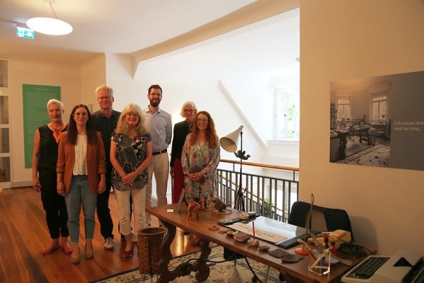 Freuen sich, dass der Schreibtisch von Hilde Domin künftig im Morata-Haus ausgestellt wird (von links): Dr. Andrea Edel (Leiterin Kulturamt), Sabrina Schubert (Verwaltungsleitung Morata-Haus), Stefan Kaumkötter (Kulturamt), Marion Tauschwitz (Domin-Biografin und Nachlassverwalterin), Dr. Steffen Götze (Studienleiter am Morata-Haus), Prof. Dr. Sibylle Rolf (Kirchenrätin) und Monika Lehmann-Etzelmüller (Seminarleitung Predigerseminar Petersstift). Gruppe von Frauen und Männern vor einem Schreibtisch