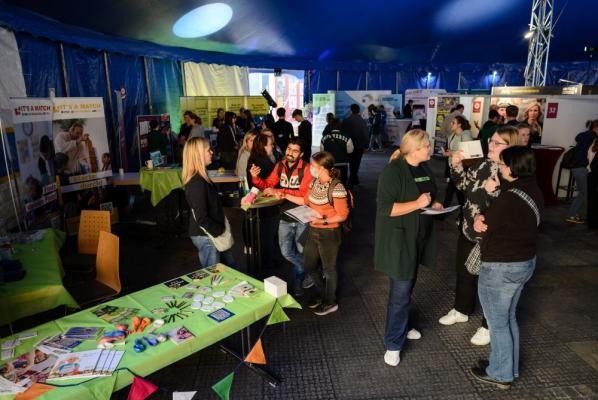Mehr als 60 Ausbildungsbetriebe präsentieren sich und ihre Ausbildungs- und Studienangebote bei den Heidelberg Ausbildungs- und Studientagen am 14. und 15. Oktober 2026 im Dezernat#16. (Bildnachweis: Stadt Heidelberg) Interessierte auf den Ausbildungs- und Studientagen. Sie versammeln sich um Messetische.