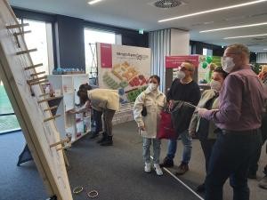Geschick war beim Wurfspiel des Amtes für Wirtschaftsförderung und Wissenschaft gefragt. (Foto: Stadt Heidelberg) Personen stehen vor einer Wurfwand, auf die Ringe geworfen werden können.
