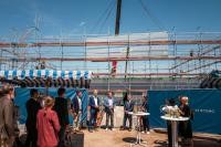 Ein Modul schwebt ein: Gemeinsam mit Gästen stehen (von links) Marc Massoth (Amtsleiter Wirtschaftsförderung Stadt Heidelberg), André Domin (Geschäftsführer Technologiepark), Oberbürgermeister Prof. Dr. Eckart Würzner, Kai Dreesbeimdiek (Geschäftsführer Gustav Zech Stiftung Management GmbH) und Johanna Michielin (Country Manager BioLabs) auf der Baustelle für den neuen Inkubator. (Foto: Dittmer) Foto von Kran auf Baustelle im Heidelberg Innovation Park