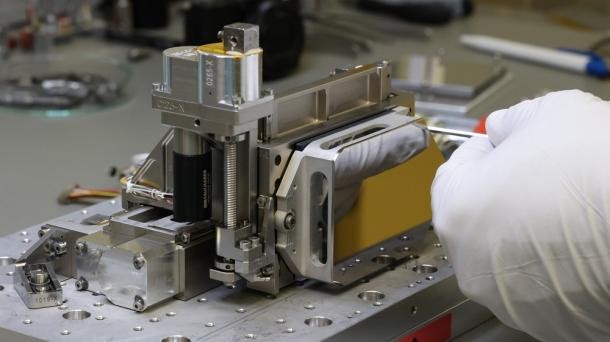 Eines von sechs Flugmodellen der Precision Alignment Mechanisms (PAM) für das Coronagraph Instrument (CGI), einer Kamera für das Weltraumteleskop Nancy Grace Roman. (Foto: O. Krause/MPIA) Eine Hand schraubt an einem Präzisionsinstrument.