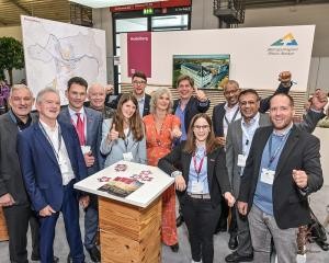 Das Team Heidelberg am Stand der Metropolregion Rhein-Neckar auf der Expo Real in München stellte Heidelberger Themen und Projekte vor, allen voran die Konversionsflächen. (Foto: Metropolregion Rhein-Neckar) Zehn Menschen stehen vor Messewänden.