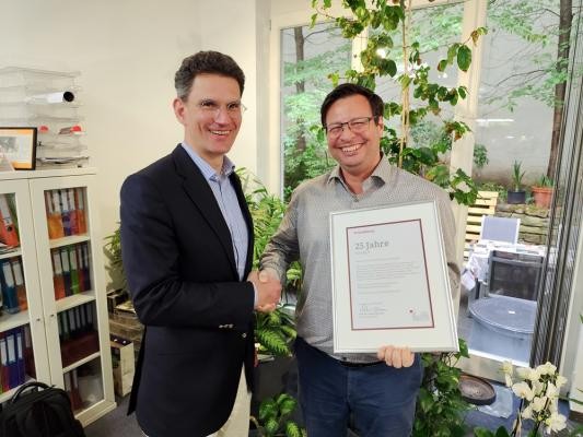 Marc Massoth gratuliert Christian Koinegg zum Firmenjubiläum. (Foto: Stadt Heidelberg) Marc Massoth gratuliert Christian Koinegg zum Firmenjubiläum, schüttelt ihm die Hand, beide lachen in die Kamera.