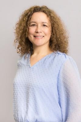 Melanie Tauber. (Foto: Sabine Arndt) Eine Frau mit Locken und einer hellblauen Bluse schaut freundlich in die Kamera und lächelt.