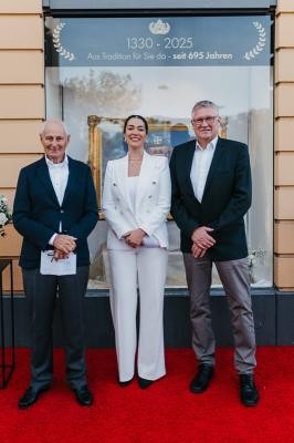 Drei Inhabergenerationen versammelt: Dr. Dieter Hof (v.l.), Dr. Parniyan Alamdari und Oliver Teichmann vor der Hof-Apotheke. (Foto: Alamdari) Zwei Männer und eine Frau stehen vor einer Apotheke und schauen in die Kamera.
