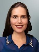 Foto von Nora Welsch Eine lächelnde Frau mit dunklen langen Haaren und einer dunkelblauen Bluse