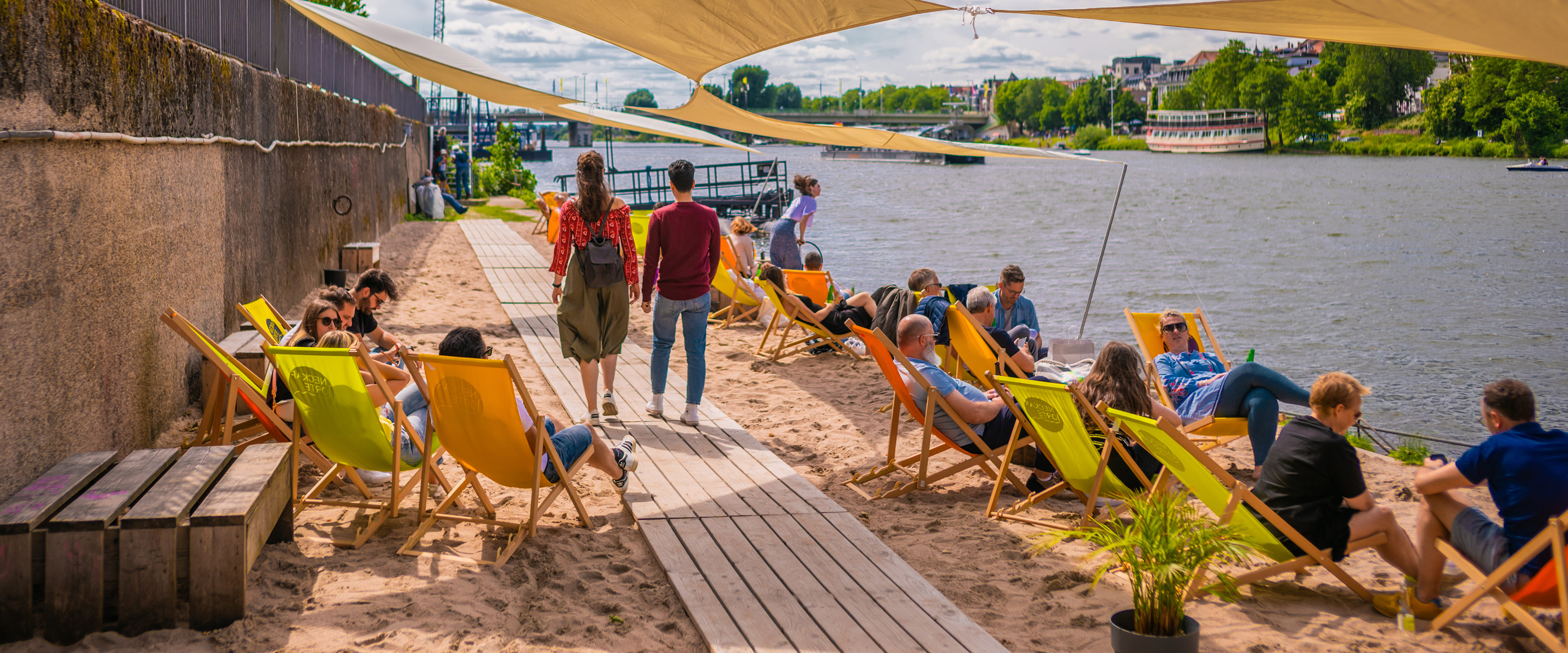 Sandstrand am Neckar mit Sonnensegel, Schiff und Menschen am Ufer