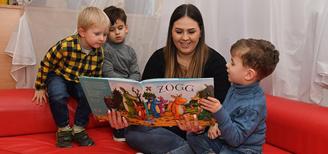 Kinder mit Erzieherin beim Vorlesen