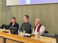 Drei Personen sitzen nebeneinander, einer hält einen Vortrag Drei Personen sitzen nebeneinander, einer hält einen Vortrag