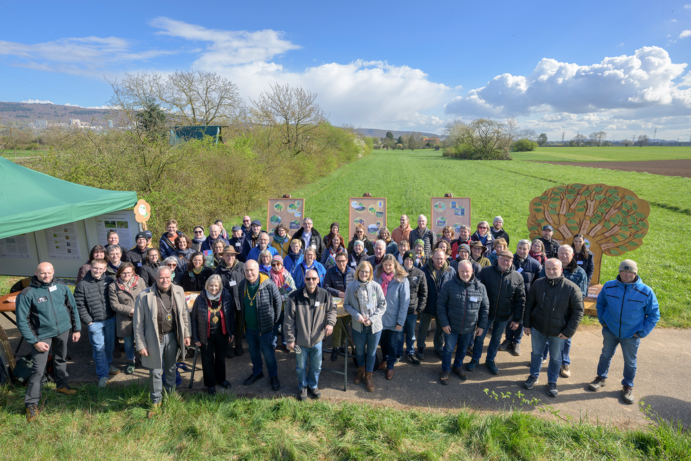 Eine Frau, die vor einem großen Buch sitzt und ein Mann, der daneben steht. 