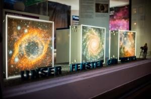 In einem Schaufenster stehen Fotos von Galaxien und die Buchstaben "Unser Fenster zum Weltall".