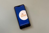 Ein Handy-Display zeigt das Logo der NINA-App.