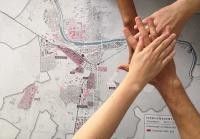Vier Hände liegen übereinander über einer Karte von Heidelberg.