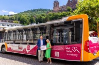 Marc Massoth und Iris Schiller vom Amt für Wirtschaftsförderung und Wissenschaft stehen vor dem Bus im "Vielmehr Heidelberg"-Design. 