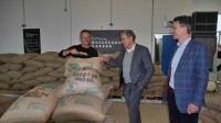Oberbürgermeister Prof. Dr. Eckart Würzner (M.) und Marc Massoth (r.) vom Amt für Wirtschaftsförderung und Wissenschaft lassen sich von einem weiteren Mann einen Sack Kaffee zeigen. 