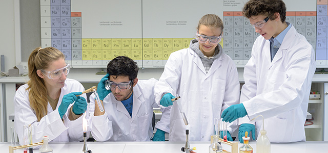 Ältere Schüler in weißen Kitteln beim Chemie-Experiment (Foto: Rothe)
