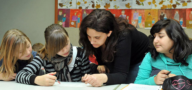 Drei Schüler in einem Klassenzimmer mit einer Lehrerin, die sie beim Lernen unterstützt. (Foto: Dorn)